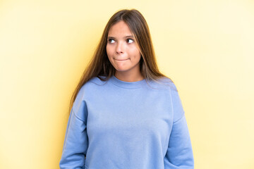 Fototapeta premium Young caucasian woman isolated on yellow background having doubts while looking up