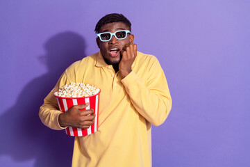 Photo portrait of attractive young man watch horror movie eat popcorn dressed stylish yellow clothes isolated on violet color background