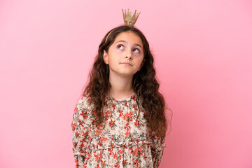 Little caucasian princess with crown isolated on pink background and looking up