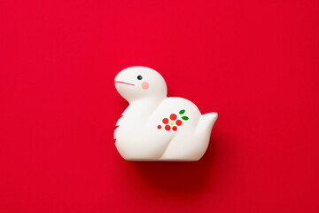 Japanese new year material. Zodiac Snake.  Snake figurine on the red background.  日本のお正月素材。干支の巳（ヘビ）。赤背景上の巳の置物