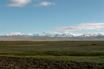 Lush green farmland with brown plowed soil in the sacred valley with the snow capped andes...