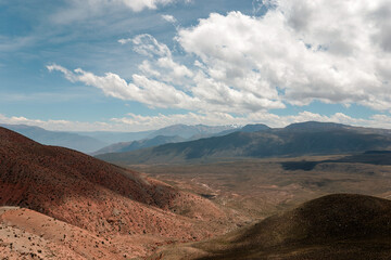 Stunning panorama of the andes mountains, painted in red and brown, under a vast sky with dramatic clouds