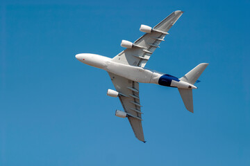 Passenger jet gracefully banks in a clear blue sky, showcasing modern aviation technology and...