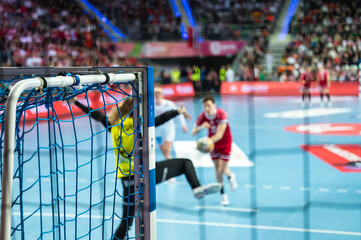 Detail of handball goal post with net and game in the background.