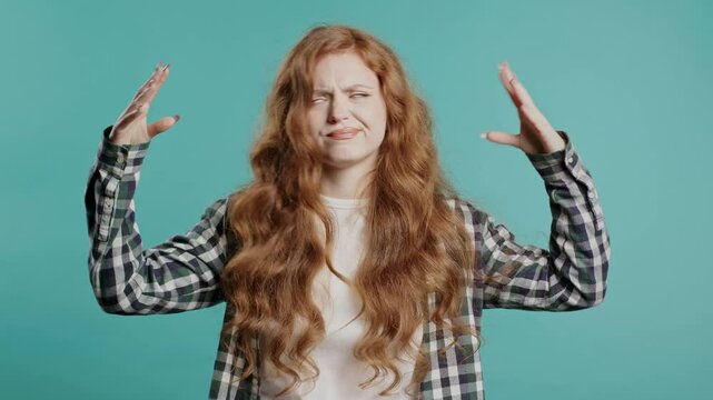 Annoyed 20s aged woman showing bla-bla-bla gesture with hands on blue background