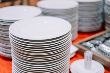 A stack of clean plates and spoons neatly arranged on a buffet table
