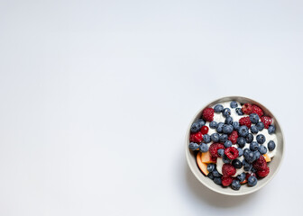 red and blue berries in the bowl in tha white background with a space for lattering. healthy...