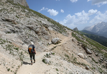 hiker with a backpack and hiking shoes walks on a trail in the Dolomites mountains of the European...
