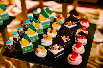 Hundreds of colorful, cute-shaped sweet pastries displayed on a table, ready to be served to guests.