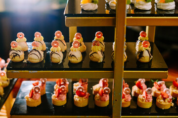 Hundreds of colorful, cute-shaped sweet pastries displayed on a table, ready to be served to guests.