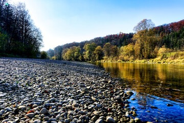 Image of an autumnal scene with bright colors and a river, forest and blue sky with clouds