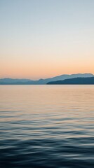 Fototapeta premium Tranquil Water Surface with Distant Mountain Range at Sunset.