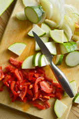 chopped courgette, chopped onion, chopped red bell peppers, wooden chopping board and silver knife, top view, close up, detailed, copy space