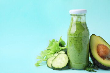 Tasty green smoothie in bottle and products on light blue background, closeup. Space for text
