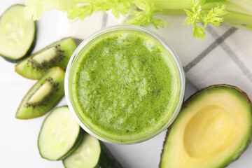Delicious green smoothie and ingredients on white table, top view
