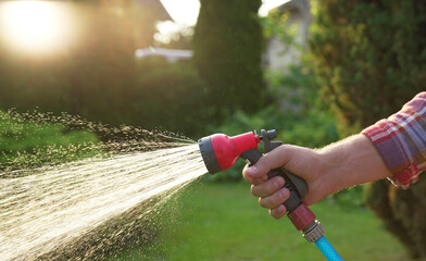 Man watering lawn with hose in backyard, closeup