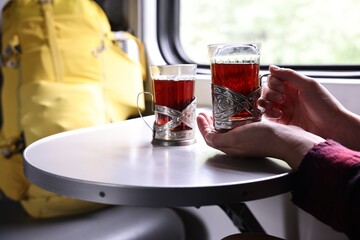 Young woman with cups of tea at table in train, closeup