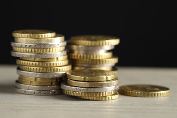 Stacked coins on wooden table against black background, closeup. Salary concept
