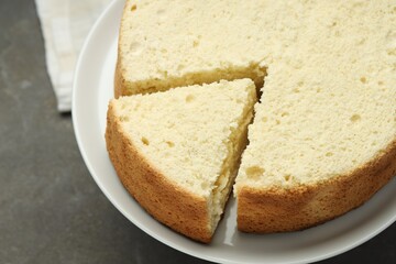 Tasty cut sponge cake on grey table, closeup