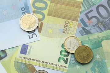 Different coins on euro banknotes, top view