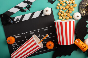 Movie clapperboard and Halloween decorations with popcorn on green background,  pop corn and sweet...