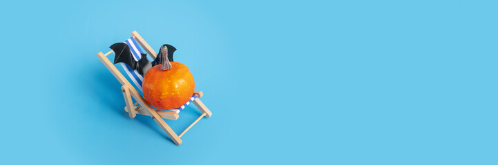 Halloween travel, pumpkin on a beach chair, spooky summer vacation, orange decoration, scary holiday event.