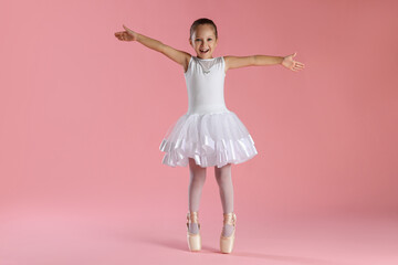 Naklejka premium Little ballerina practicing dance moves on pink background