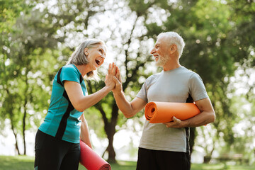 Happy senior couple giving high five after exercising together outdoors