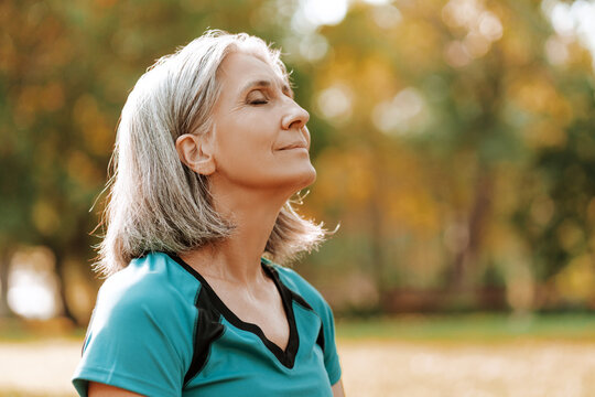Beautiful senior woman breathing fresh air in park, closeup outdoors, copy space