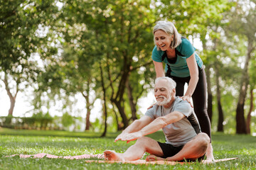 Fototapeta premium Senior couple is doing stretching exercises in the park, together training outdoors