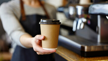 Coffee to go in hand of barista in coffee shop