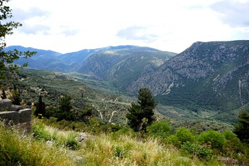 Ancient Greek ruins of the temple complex of the Oracle of Delphi in Greece with a breathtaking view of the panorama of the Pleistos River valley on a sunny summer's day 