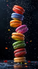 A stacked tower of rainbow-colored macarons floats mid-air, surrounded by falling crumbs, creating a vibrant and artistic dessert moment.