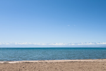 Sandy beach and panoramic view of Lake Issyk-Kul in Kyrgyzstan.