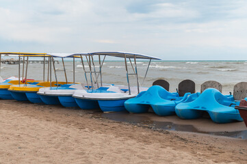 Pleasure catamprans on a sandy beach and storm waves on Lake Issyk-Kul in Kyrgyzstan.