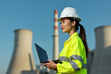 Obraz premium construction worker with outfit holding smart mobile tablet with factory building in background, generative AI