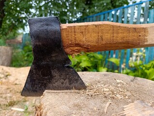 A large axe with a wooden handle sitting on top of a tree stump