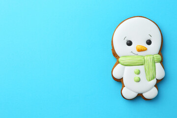 Tasty Christmas cookie in shape of snowman on light blue background, top view. Space for text