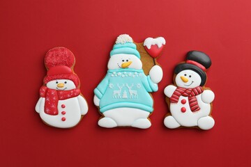 Tasty Christmas cookies in shape of snowman on red background, flat lay