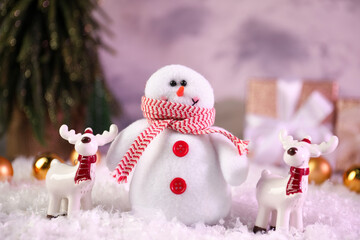 Funny snowman figure and deers on artificial snow, closeup