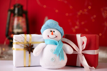 Funny snowman figure and Christmas gifts on white table