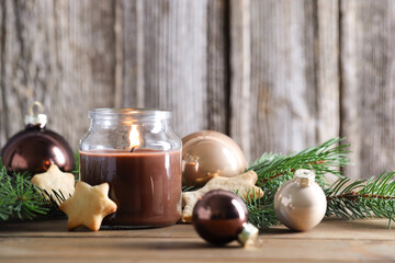 Burning candle, baubles, cookies and fir branches on wooden table. Christmas atmosphere