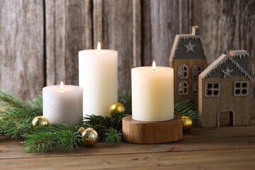 Burning candles, baubles, fir branches and other Christmas decor on wooden table