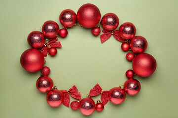 Christmas decor. Frame of shiny baubles and bows on green background, flat lay. Space for text