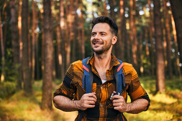 Portrait of smiling man hiking with backpack through the forest in autumn