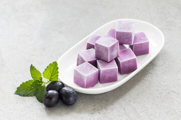 Black Grape ice cream in the form of mini cubes. On a plate. Close-up
