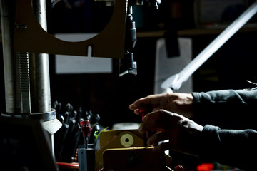Person drilling gripping holes in bowling balls. Making of professional sports equipment.