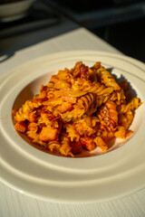 Ham and Fusilli in Rich Tomato Sauce. Savoury Italian Dish Served on a White Plate. Close-up of Flavorful Pasta Meal Ready to Eat