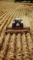 A Powerful Tractor Rakes Hay in a Field, Leaving Rows of Golden Straw Behind