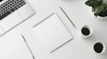 A minimalist workspace featuring a blank notepad, pencils, coffee cups, and a laptop.